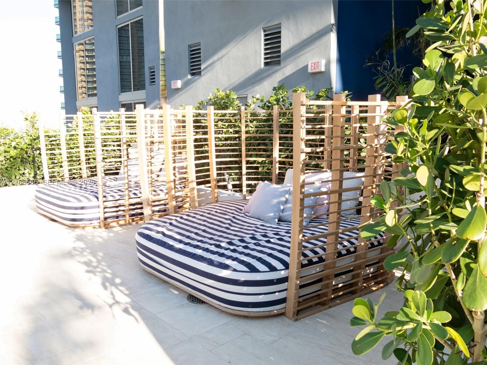 Outdoor terrace featuring stone tile flooring, custom slatted wood privacy structures, and integrated landscaping