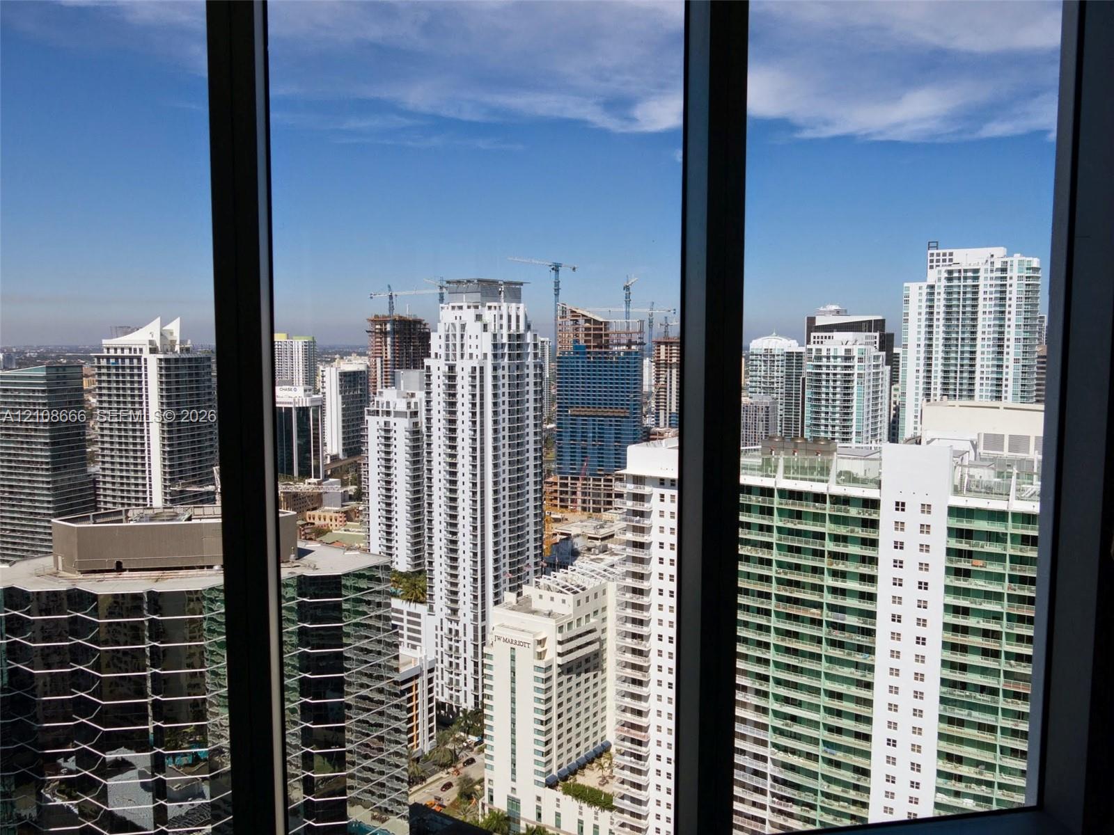 Floor-to-ceiling windows with dark-finish mullions framing an expansive cityscape