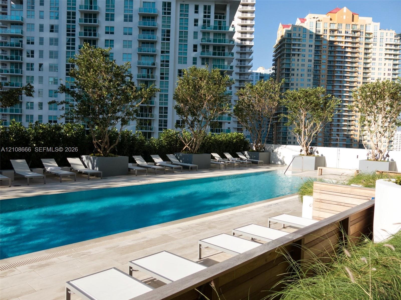 Rectangular swimming pool featuring tile decking, integrated landscaping planters, and a perimeter wall