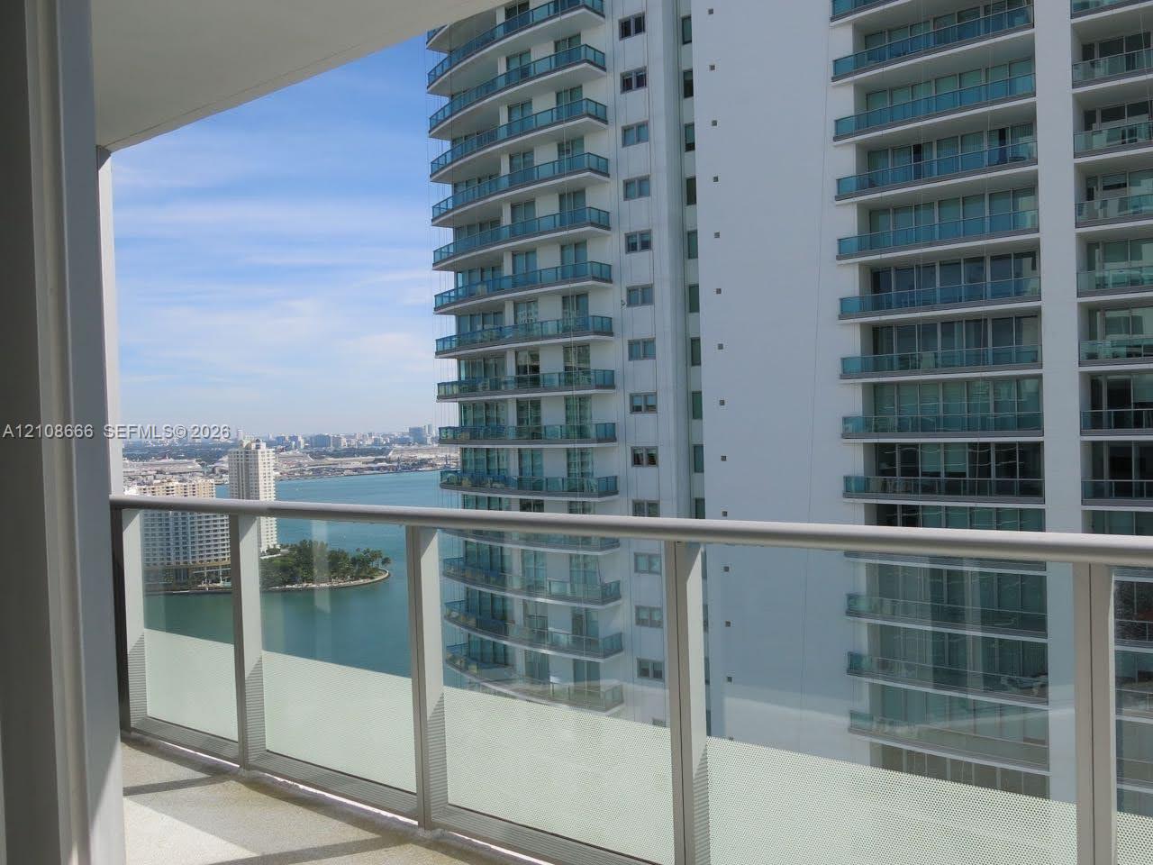 Private balcony with a glass and metal railing, concrete flooring, and water scenery Private balcony with a glass and metal railing, concrete flooring, and water scenery