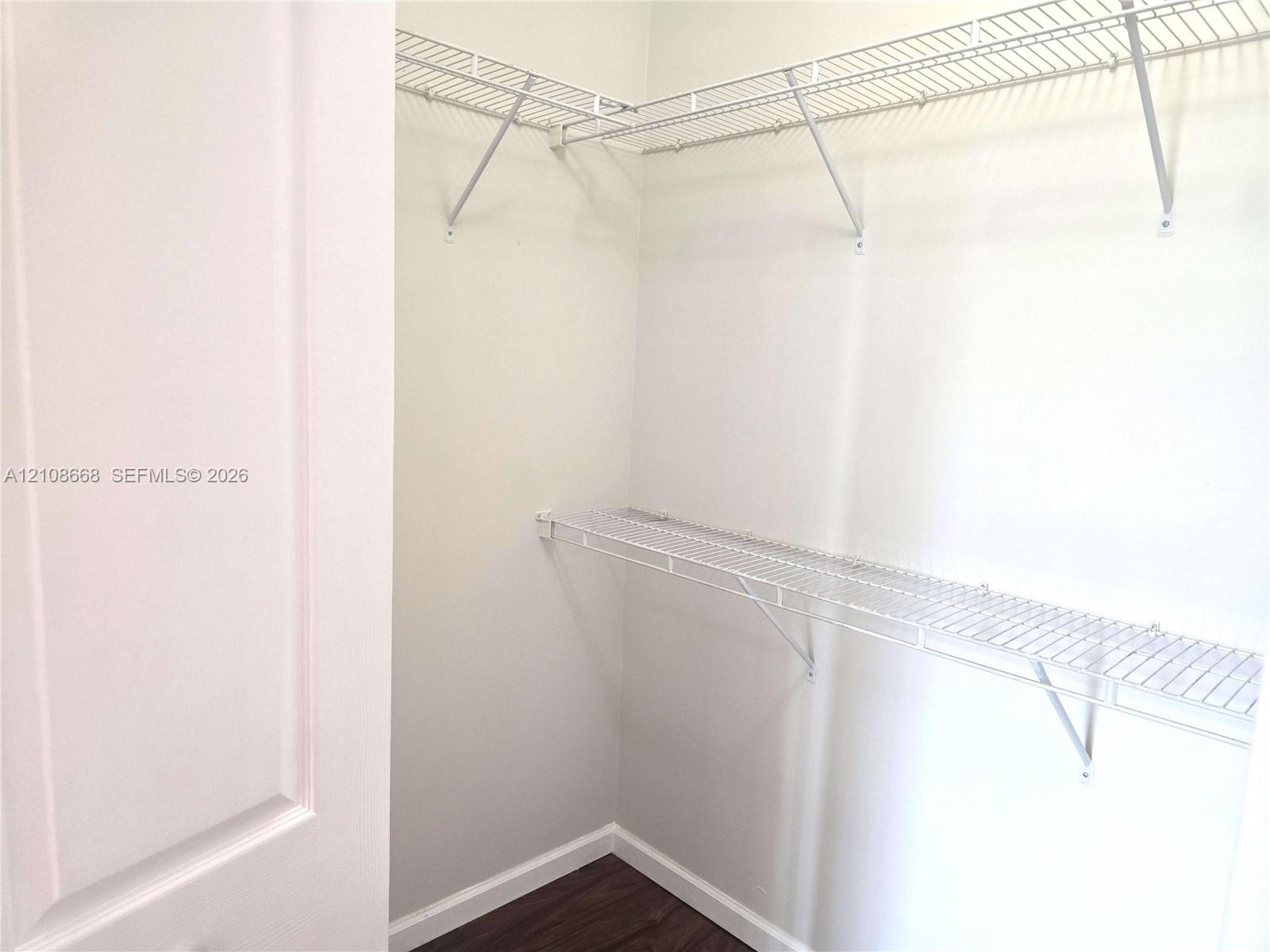 Walk-in storage space featuring wood-finish flooring and tiered white wire shelving