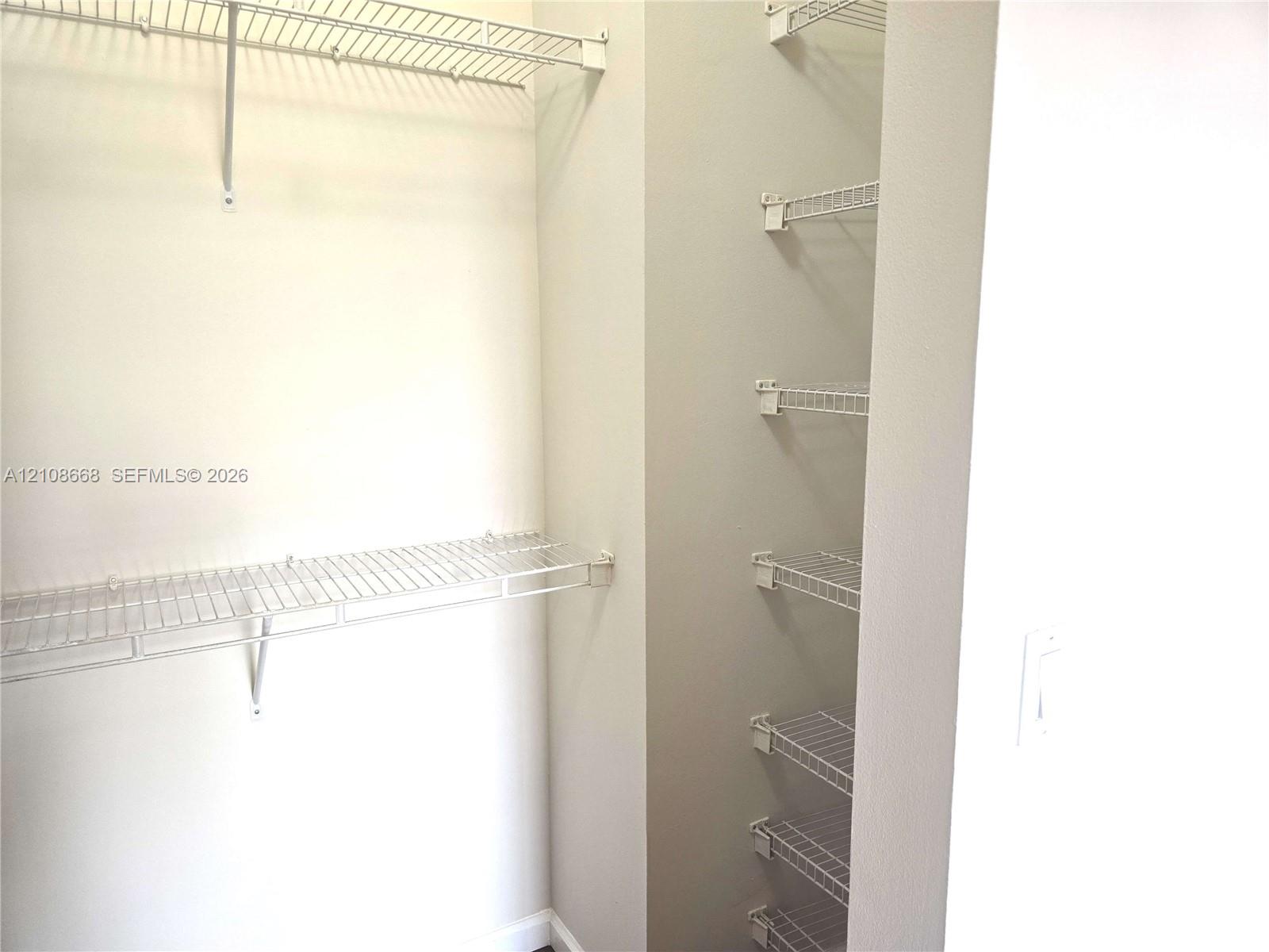 Storage area featuring white wire shelving units and wall-mounted racks