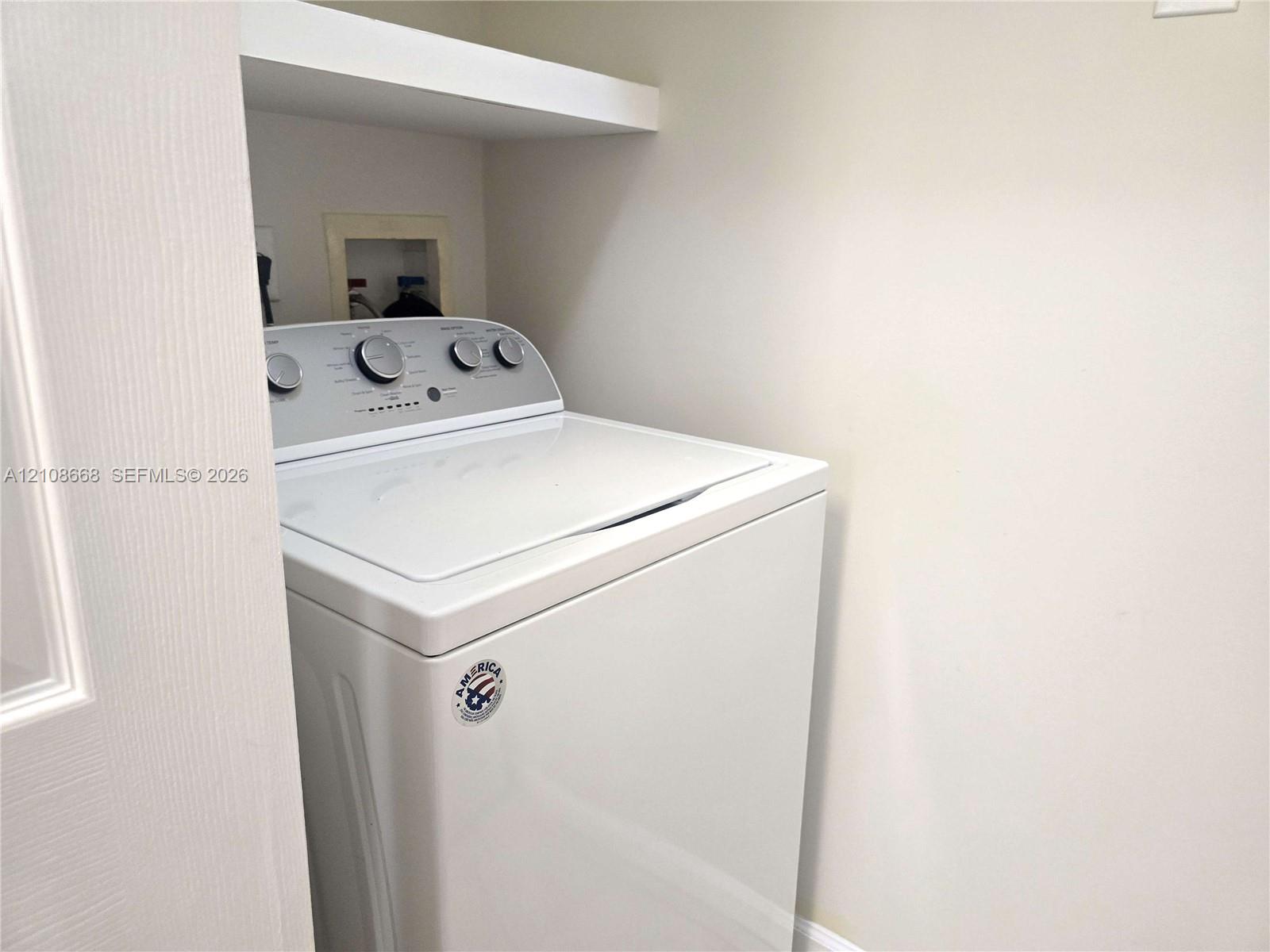 Laundry area featuring a built-in overhead storage shelf and recessed utility hookups