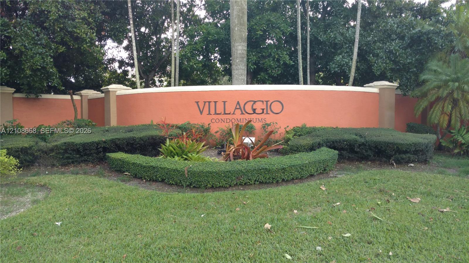 Curved stucco monument signage featuring architectural pillars and professionally maintained landscaping