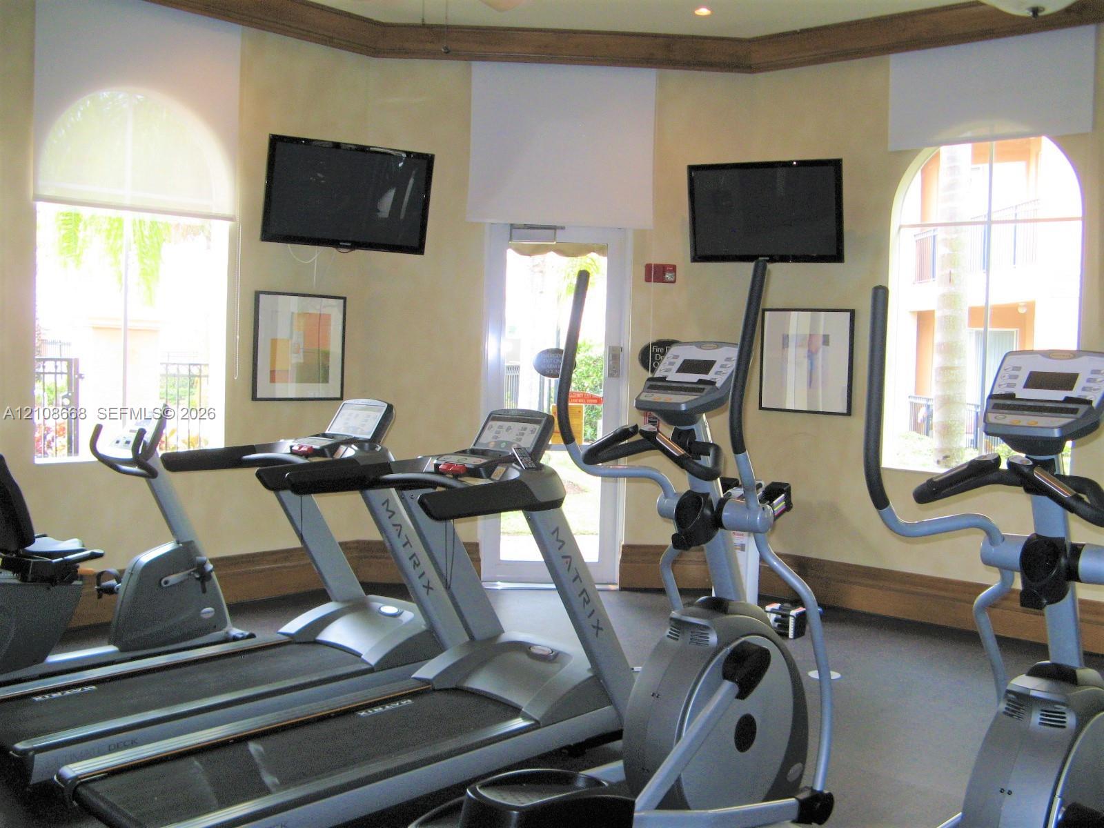 Multi-purpose room featuring arched windows, recessed lighting, wood crown molding, and a central exterior glass door