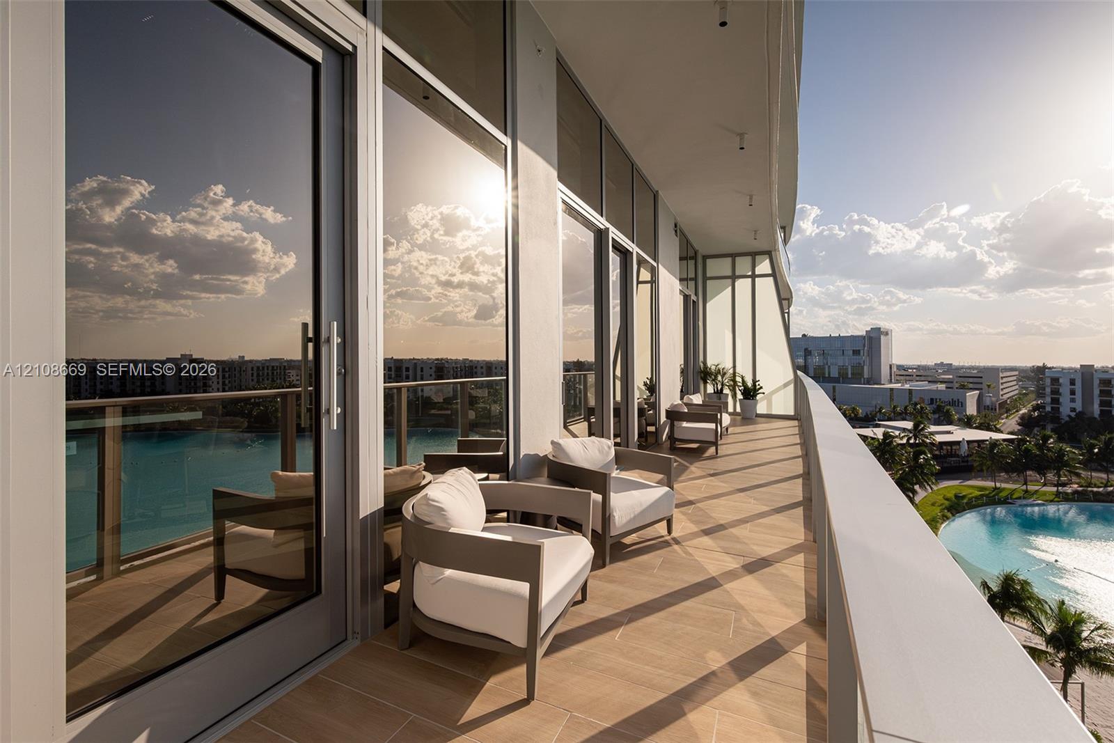 Spacious covered terrace featuring tile flooring, floor-to-ceiling glass panel doors, and a metal railing