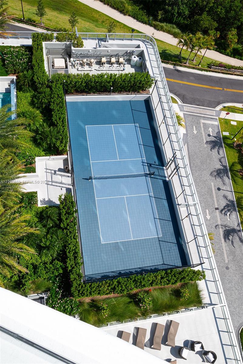 Tennis court featuring a blue hard-surface finish, perimeter fencing, and professional-grade net