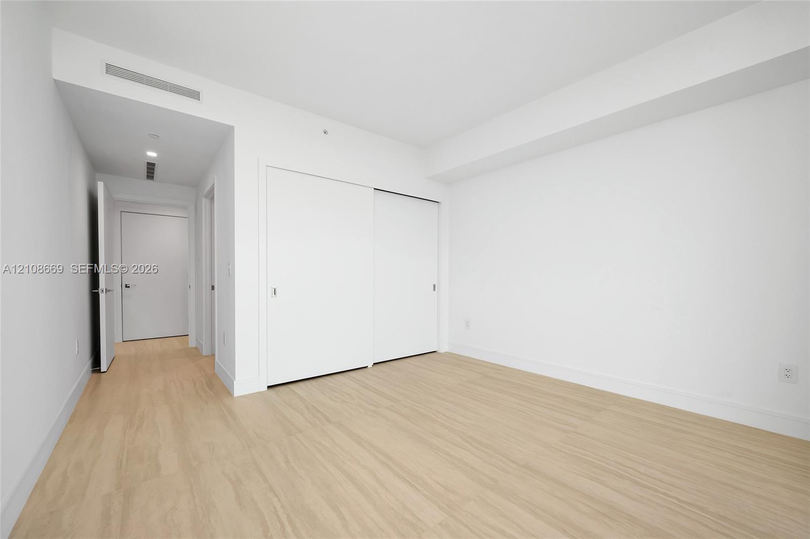 Interior space featuring wood-finish flooring, white walls, and built-in closet with sliding doors