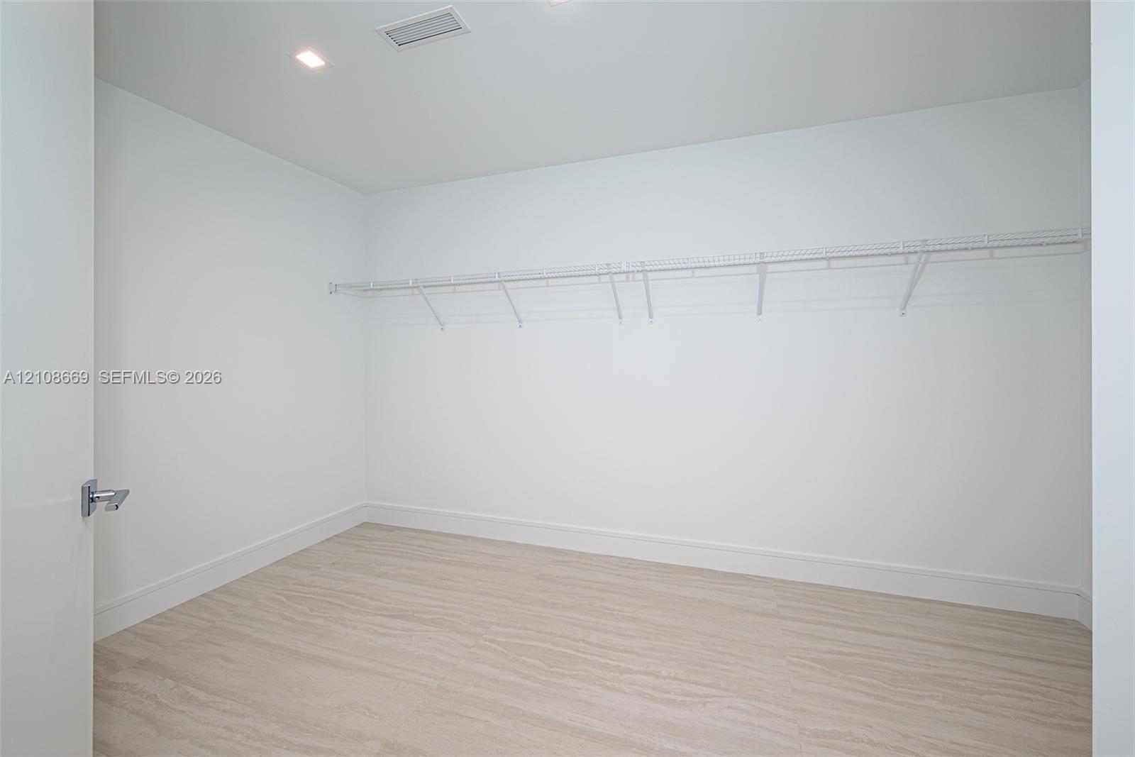 Walk-in closet featuring light wood-finish flooring, recessed lighting, and wall-mounted wire shelving
