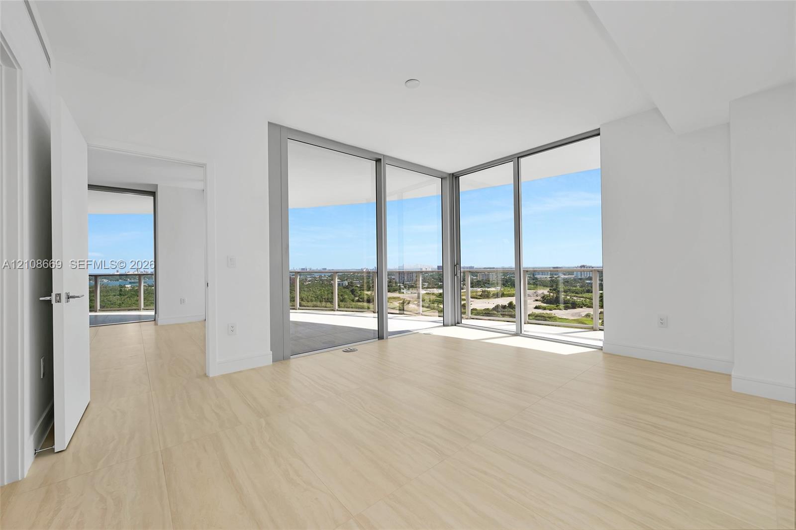 Floor-to-ceiling glass corner walls, wrap-around exterior balcony, neutral wood-finish flooring, and recessed ceiling lighting
