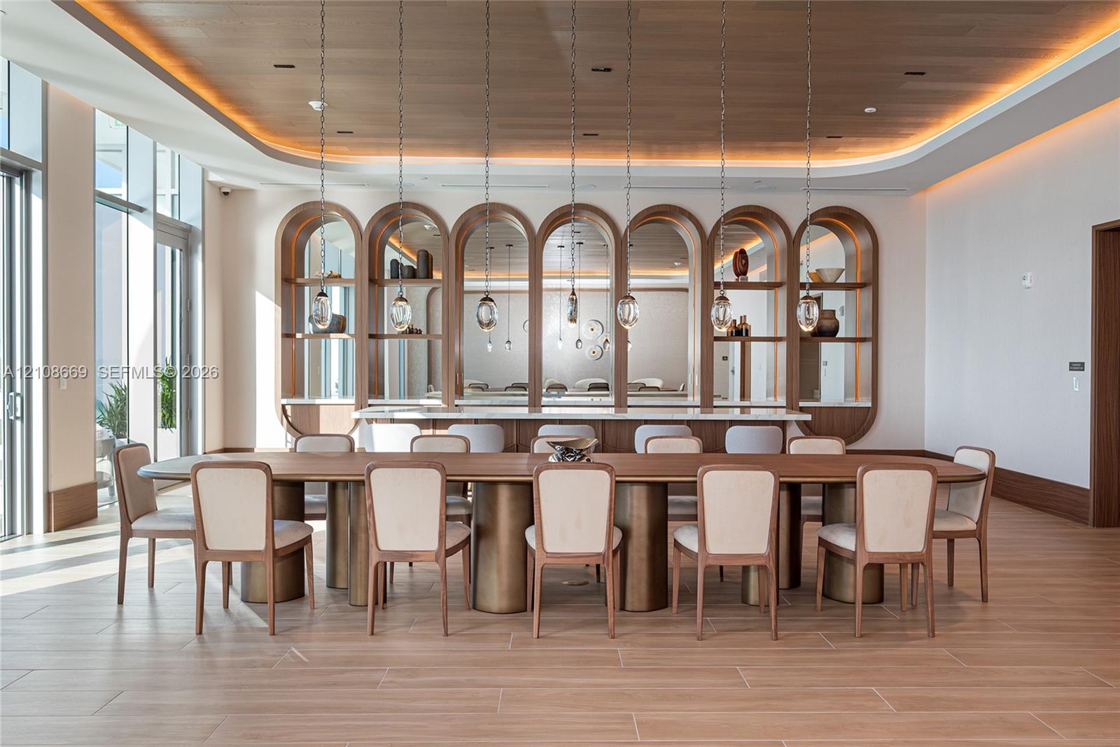 Wood-finish flooring, recessed ceiling lighting, custom arched built-in shelving, stone-topped service counter, and suspended glass pendant lighting