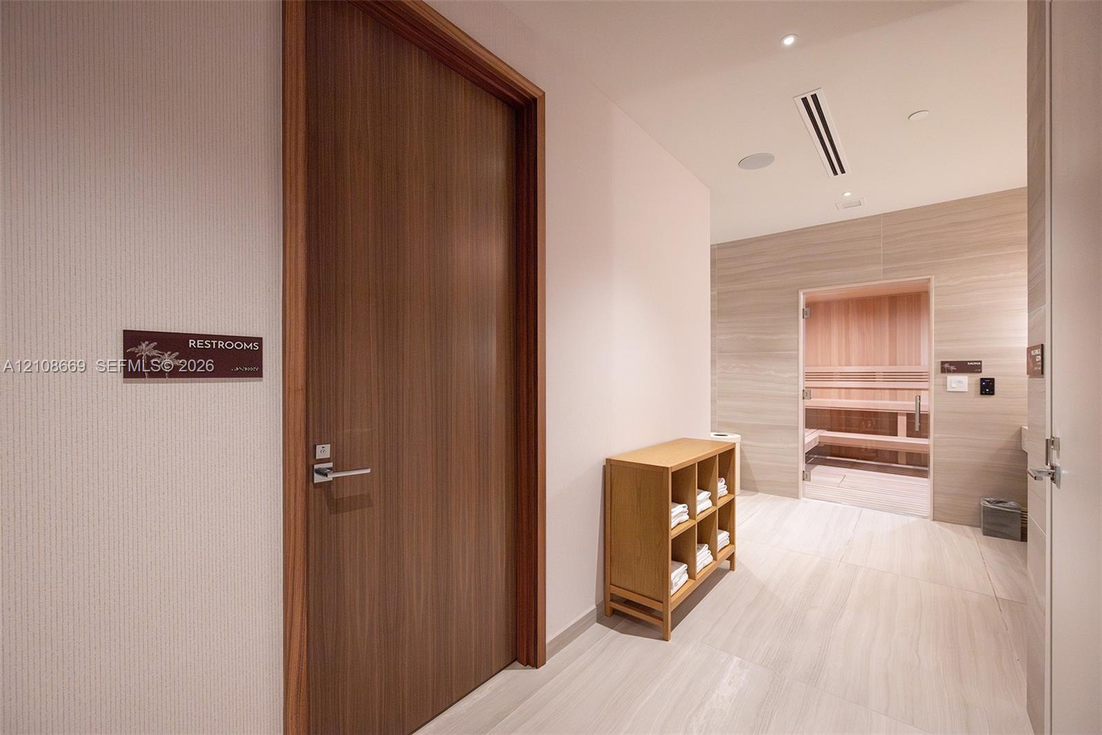 Sauna featuring interior wood paneling and integrated bench seating, complemented by large-format tile flooring and wood-finish doors