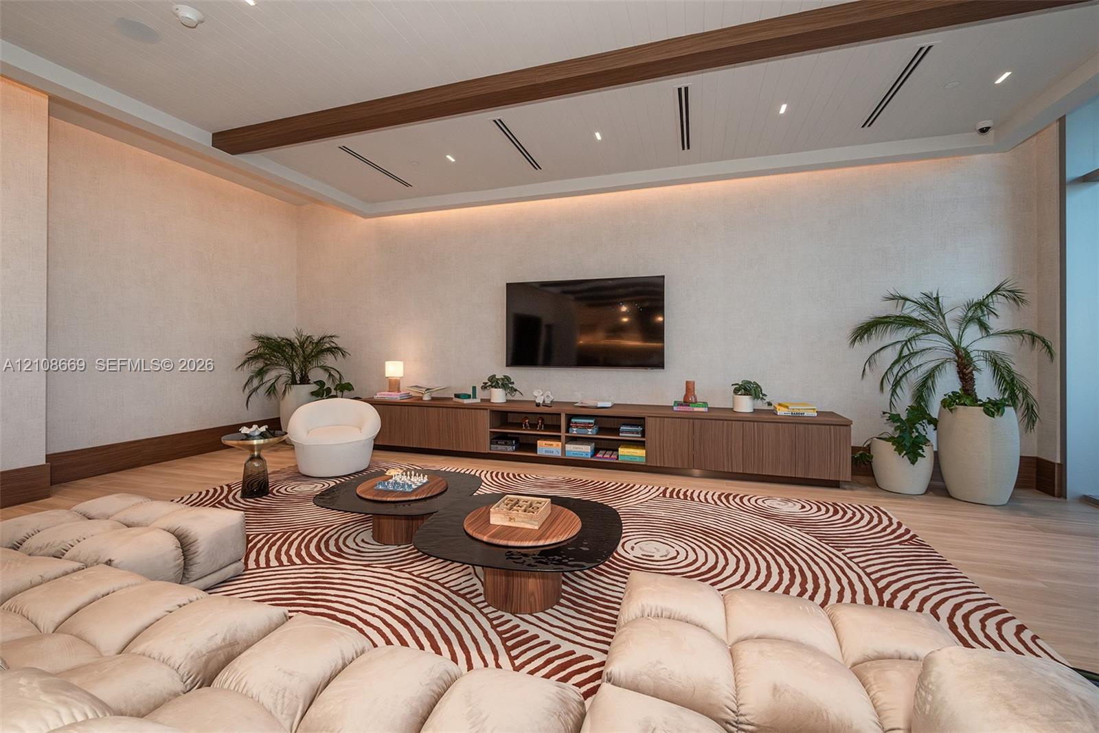 Interior space featuring recessed tray ceiling with integrated perimeter lighting, built-in horizontal cabinetry, wood-finish flooring, and minimalist linear light fixtures