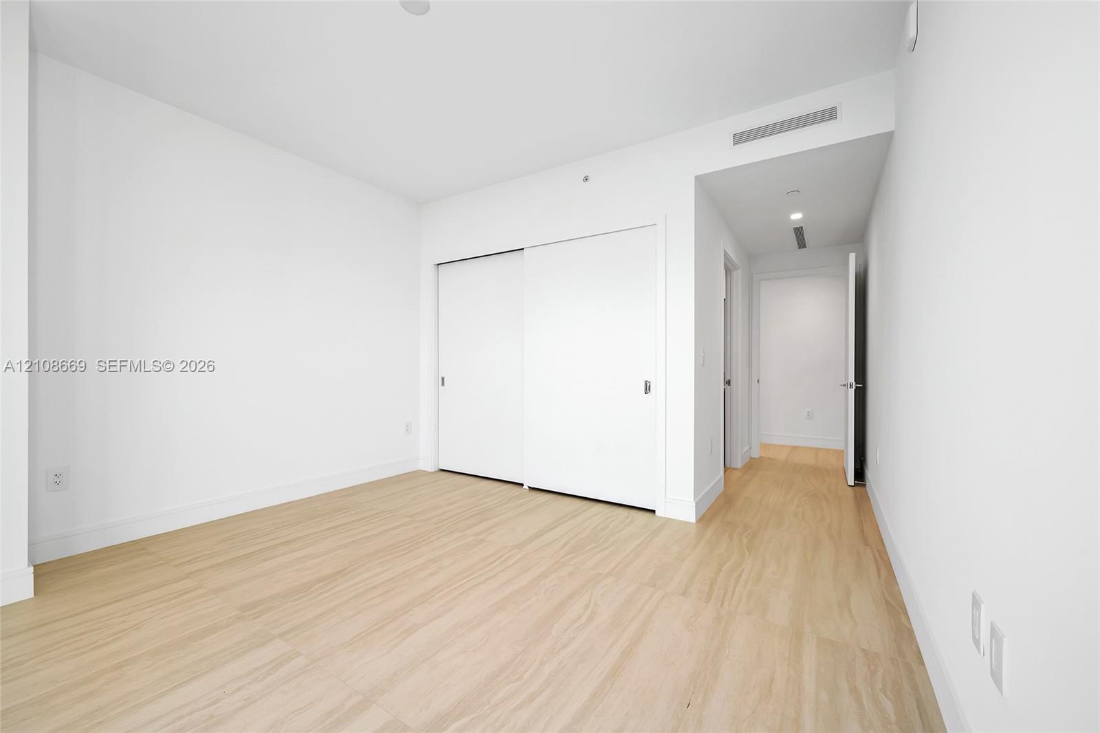 Room featuring wood-finish flooring, white walls, and a sliding-door closet