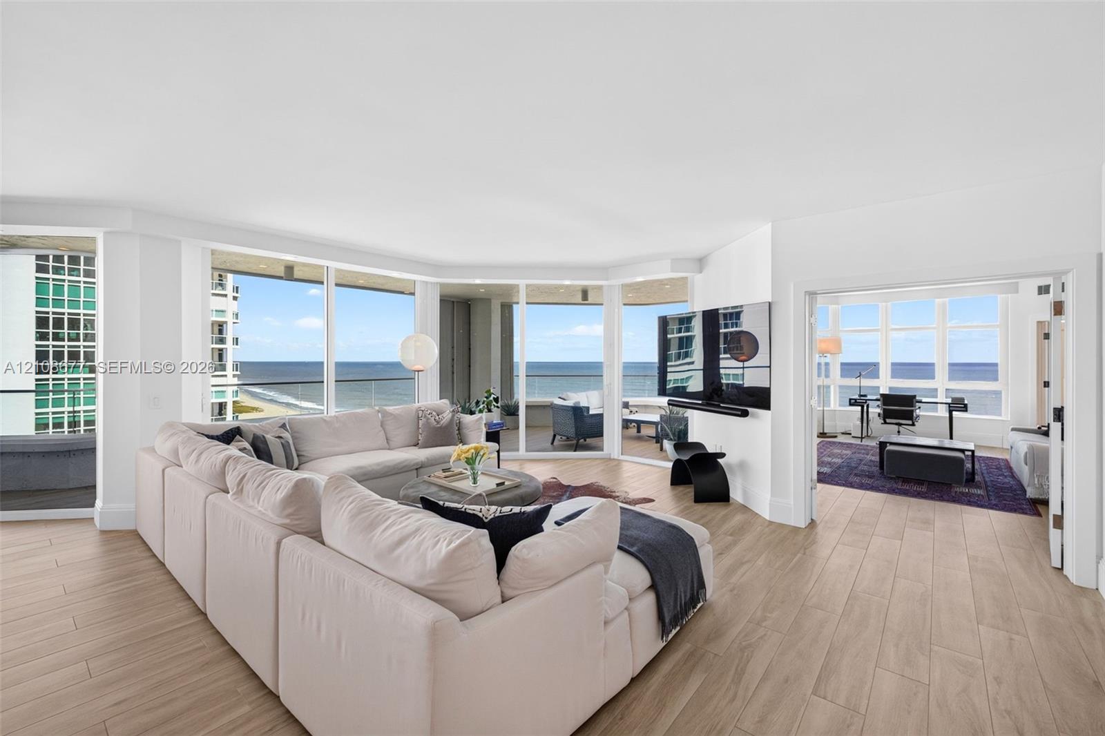 Expansive living area (and bedroom to the right, currently being used as a den) w/ hurricane impact rated floor-to-ceiling windows, wood look plank porcelain flooring, recessed lighting, and a wrap-around balcony with panoramic ocean views. Light filtering remote operated shades with Bandalux Expansive living area (and bedroom to the right, currently being used as a den) w/ hurricane impact rated floor-to-ceiling windows, wood look plank porcelain flooring, recessed lighting, and a wrap-around balcony with panoramic ocean views. Light filtering remote operated shades with Bandalux
