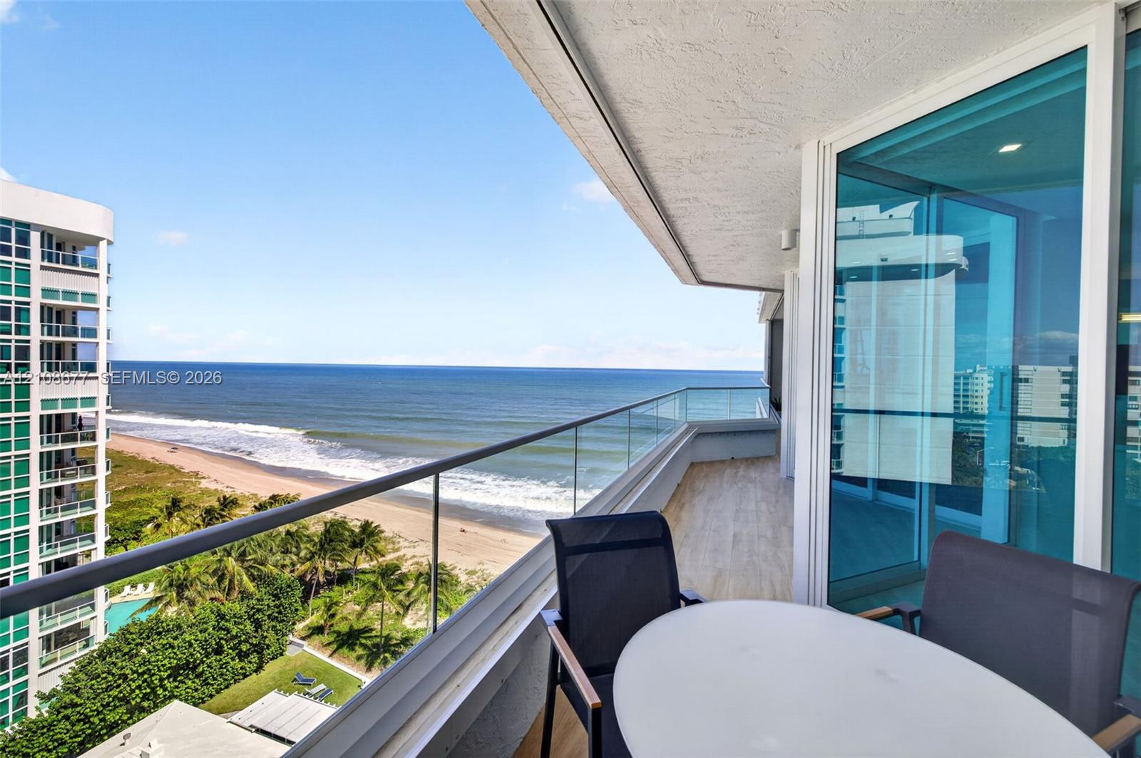 Private balcony featuring glass panel railing, tile flooring, and floor-to-ceiling glass sliding doors. Additional protection for your furniture with upgraded accordion shutters.