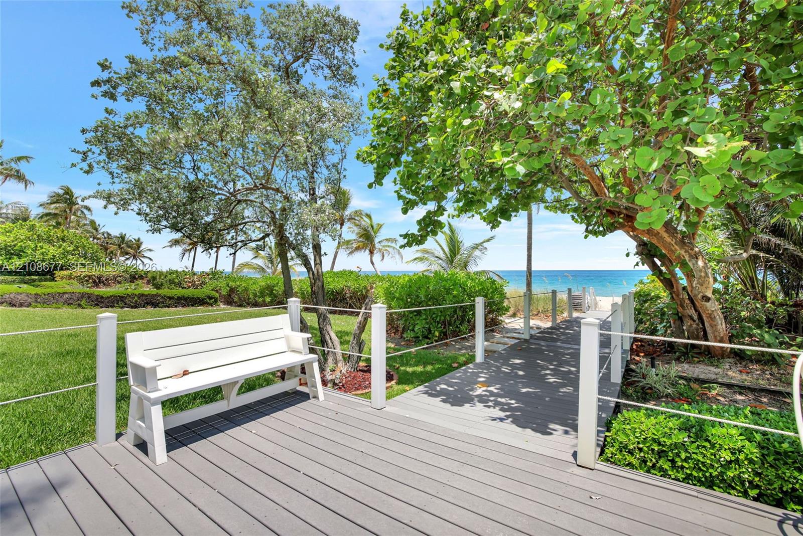 Elevated composite decking leads to mature coastal landscaping, and a direct path to the sandy oceanfront