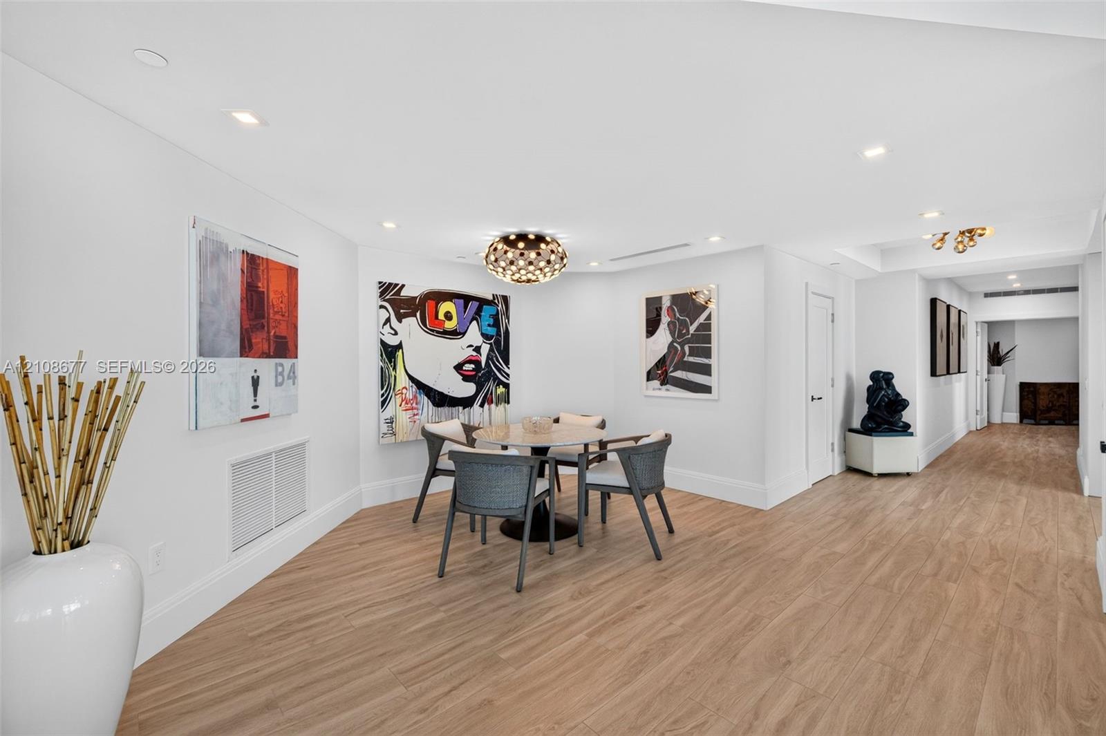Open concept informal dining area or space for your future card table, featuring wood look plank porcelain flooring, recessed lighting, and a gorgeous geometric drum ceiling fixture (upgraded fire sprinklers & linear HVAC diffusers plus beautiful tall baseboards).