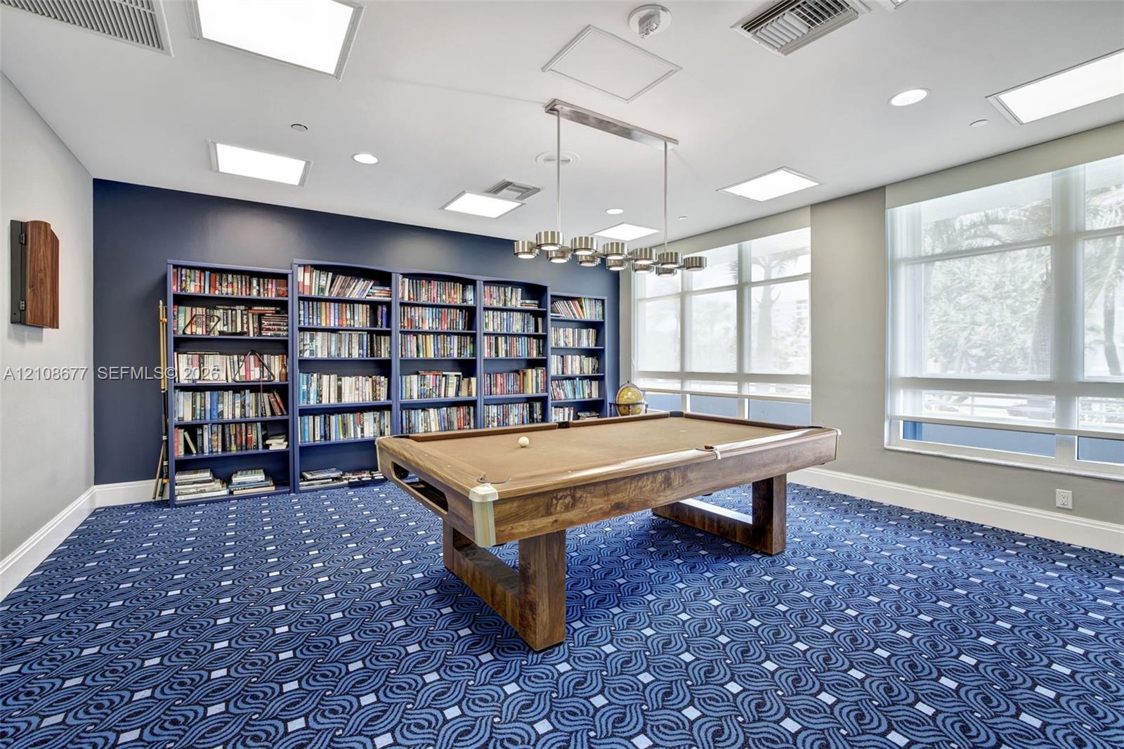 Game room / library in building w/ newer carpet, book shelving units, and pool table