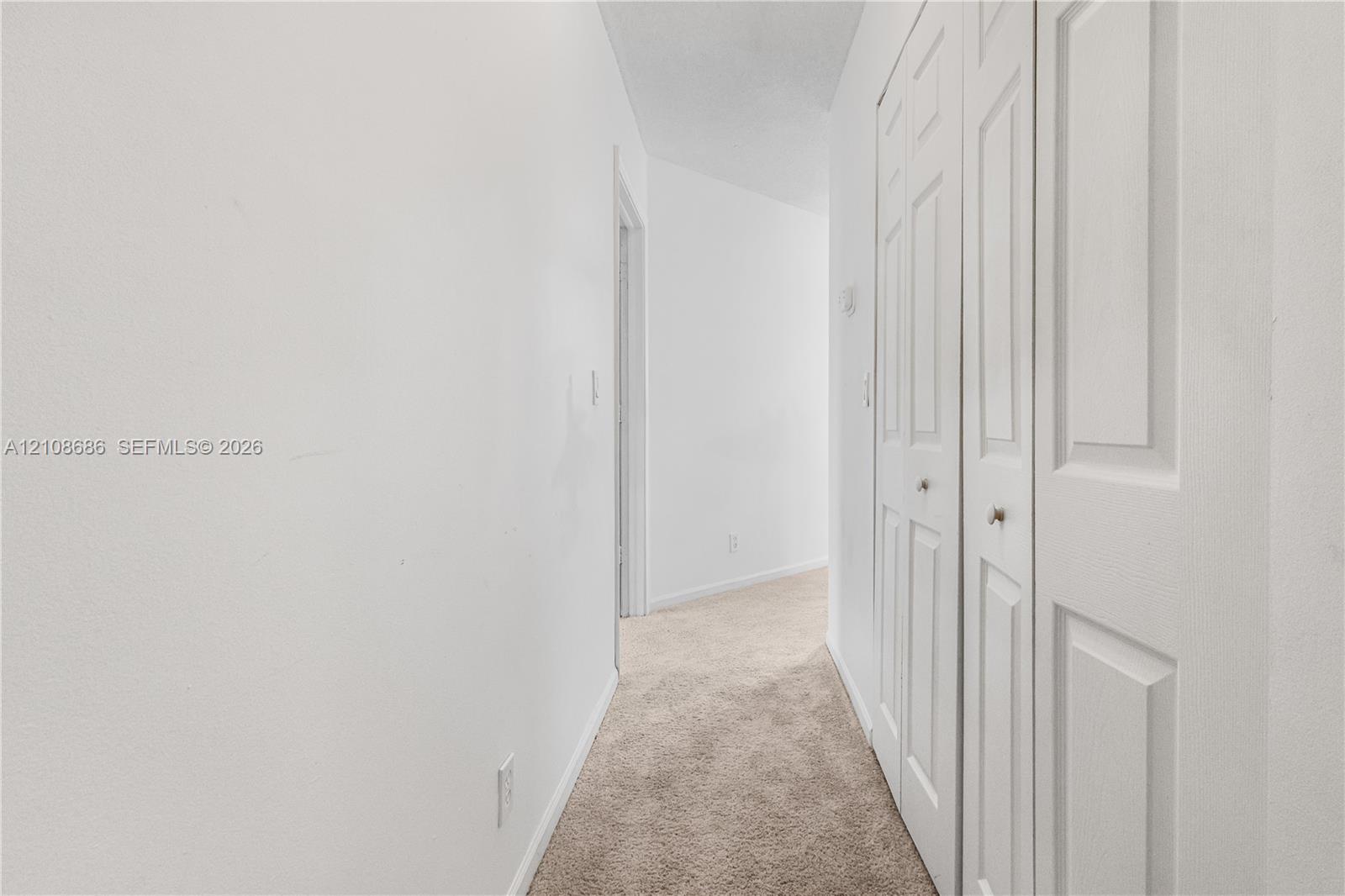Hallway featuring wall-to-wall carpeting and bi-fold closet doors Hallway featuring wall-to-wall carpeting and bi-fold closet doors