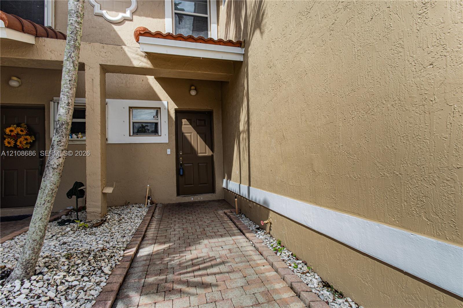 Stucco exterior featuring a brick-paver walkway, tile-capped roof accents, and a panelled entry door Stucco exterior featuring a brick-paver walkway, tile-capped roof accents, and a panelled entry door