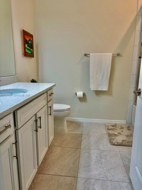 Bathroom featuring a white vanity cabinet with shaker-style doors, stone-composite countertop with an integrated basin, large-format neutral floor tile, and a wall-mounted metal towel bar