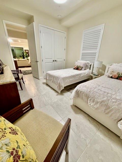 Neutral-toned large-format tile flooring, double-door closet with paneled detail, and plantation shutter window coverings