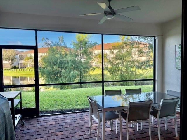 Screened-in lanai featuring paver flooring, a ceiling fan, and expansive glass screen panels overlooking water