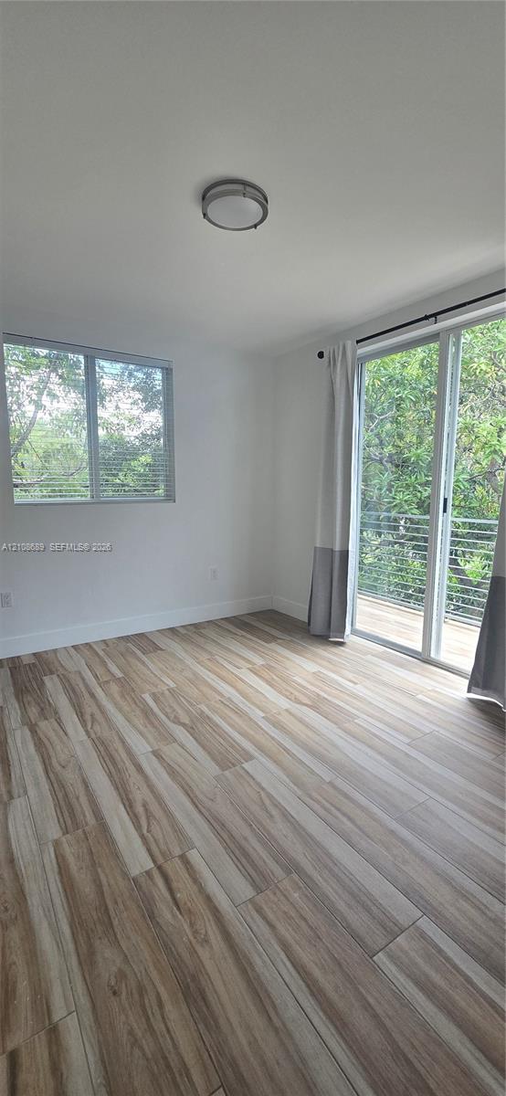 Wood-finish flooring, sliding glass door with external railing, single-hung window, and flush-mount ceiling lighting Wood-finish flooring, sliding glass door with external railing, single-hung window, and flush-mount ceiling lighting