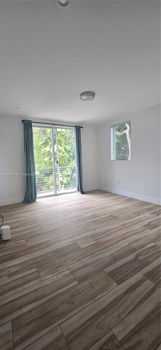 Room featuring wood-finish flooring, sliding glass door with metal railing, and recessed ceiling lighting