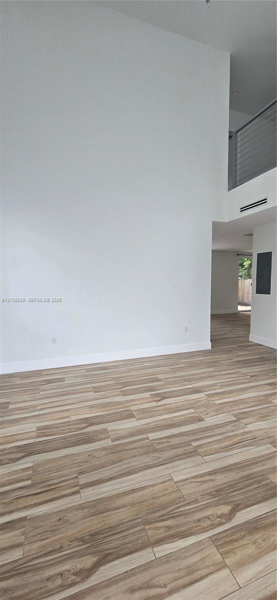 High-ceiling interior space featuring wood-finish flooring and a metal railing mezzanine High-ceiling interior space featuring wood-finish flooring and a metal railing mezzanine