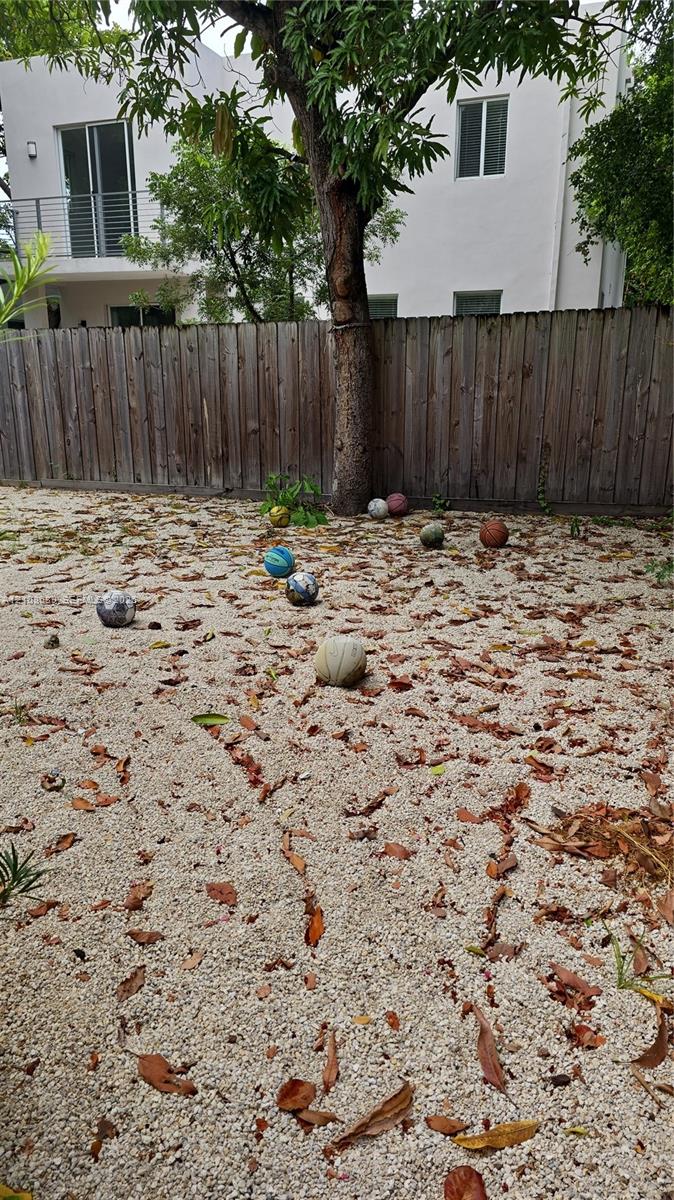 Backyard featuring white gravel ground cover, a wood privacy fence, and a mature tree