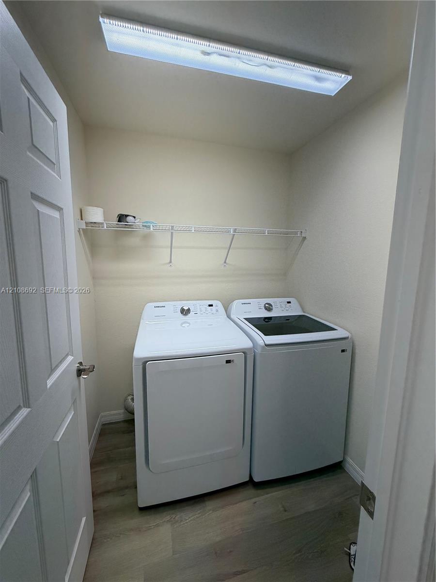 Laundry area featuring wood-finish flooring, white paneled door, and wall-mounted wire shelving