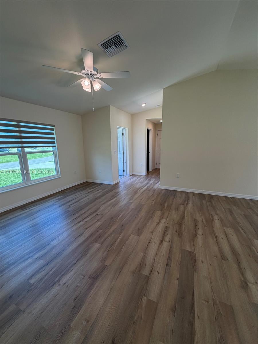 Vaulted ceilings, wood-finish flooring, ceiling fan with integrated lighting, and multi-paned windows featuring adjustable blinds