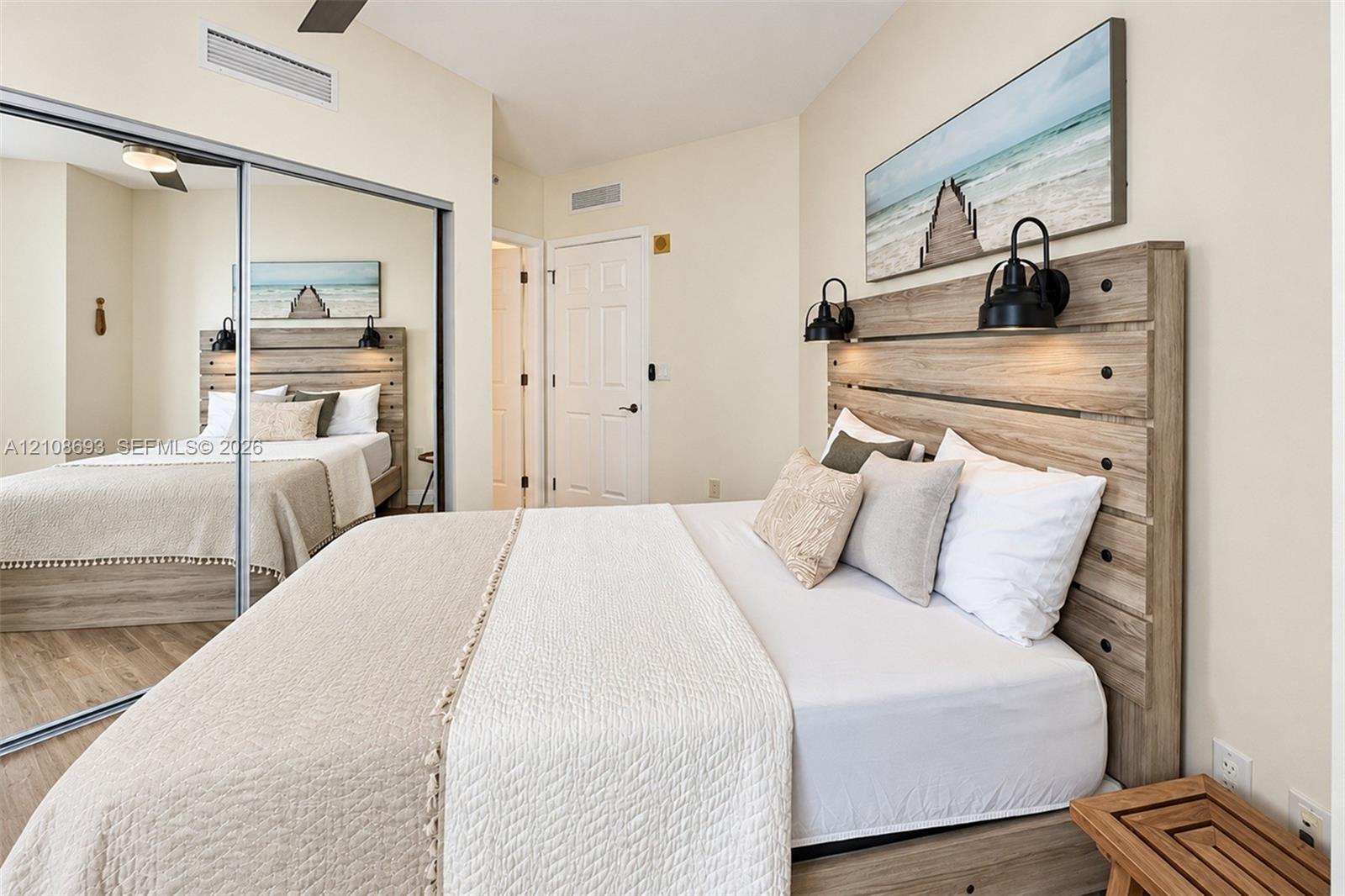 Room featuring wood-finish flooring, a full-length mirrored closet, and two wall-mounted metal light fixtures
