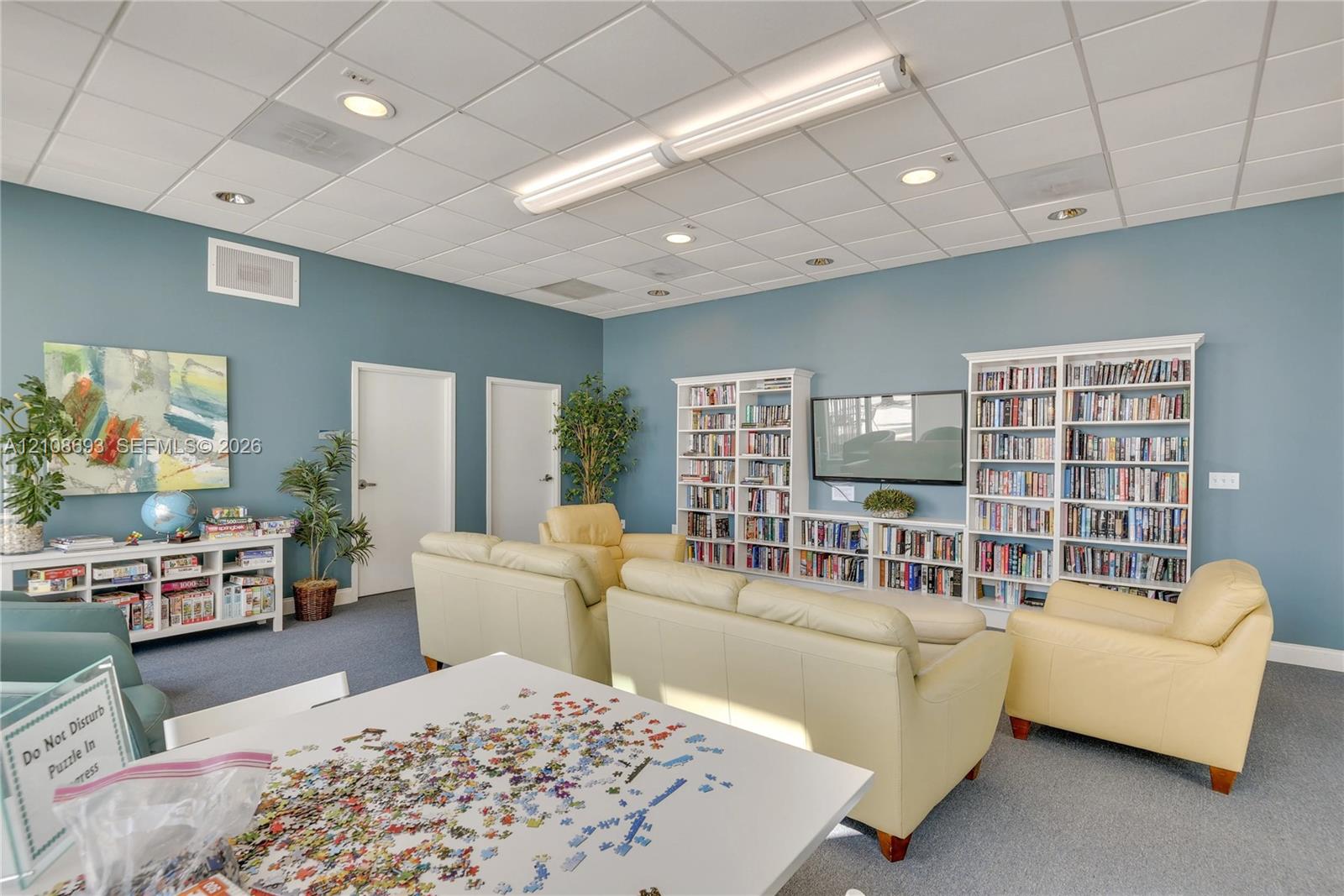 Expansive room featuring wall-to-wall built-in shelving, high-set acoustic tile ceiling, and recessed lighting