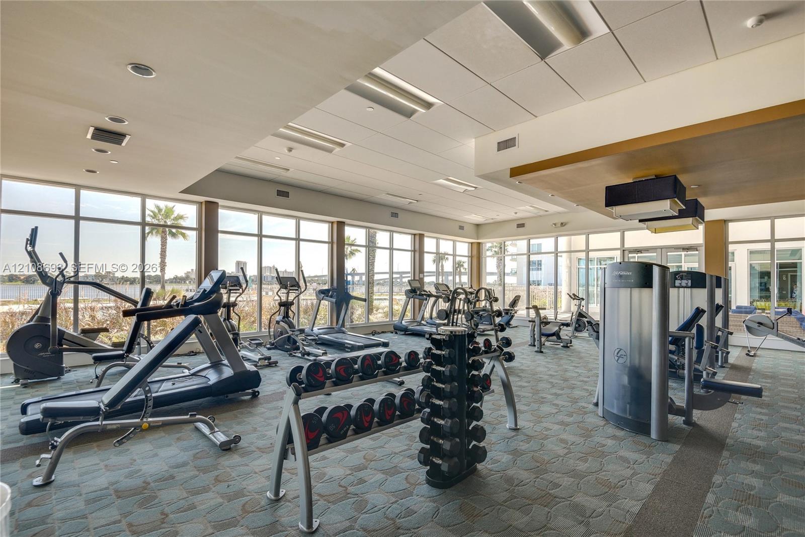 Fitness center featuring floor-to-ceiling windows, recessed lighting, and patterned carpeting