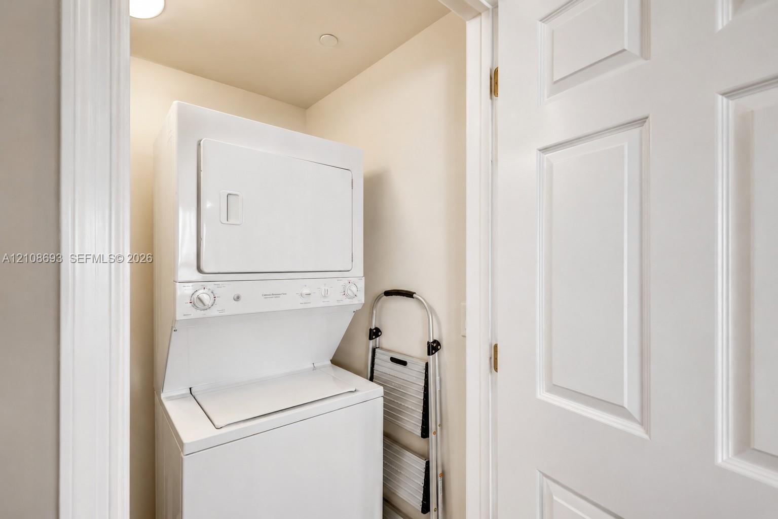Stacked laundry unit enclosed within a dedicated utility closet featuring a white paneled door
