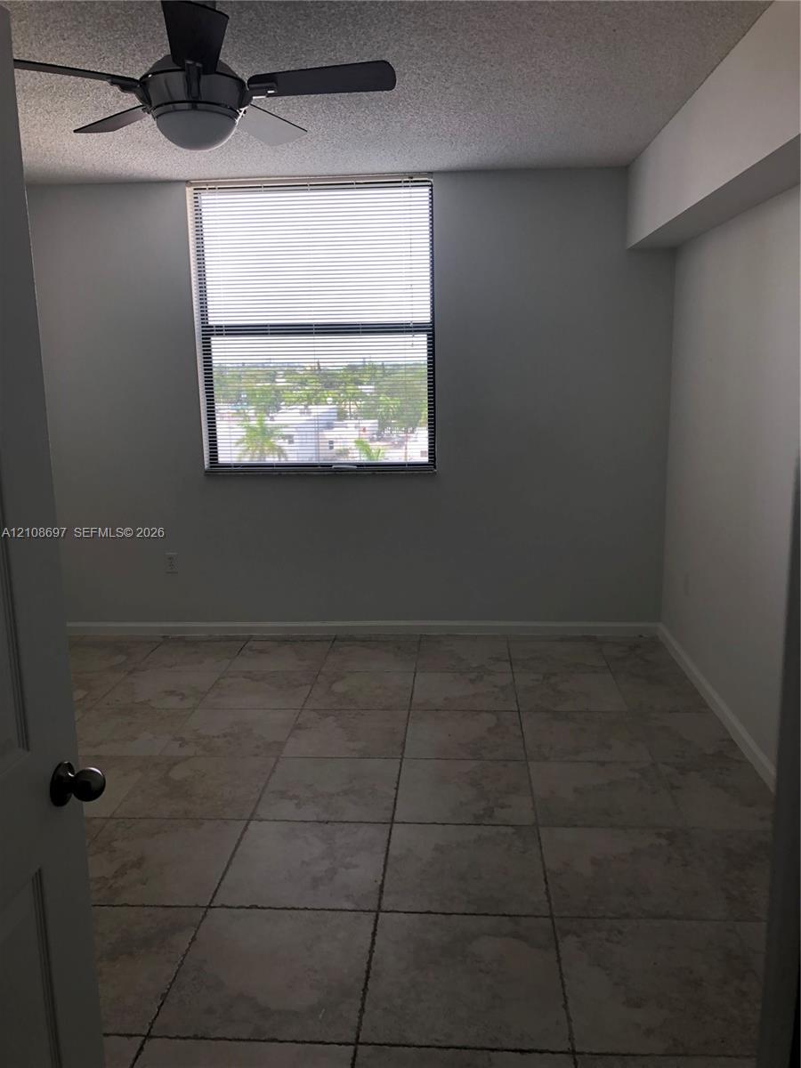 Neutral-toned tile flooring, multi-light ceiling fan, and large picture window