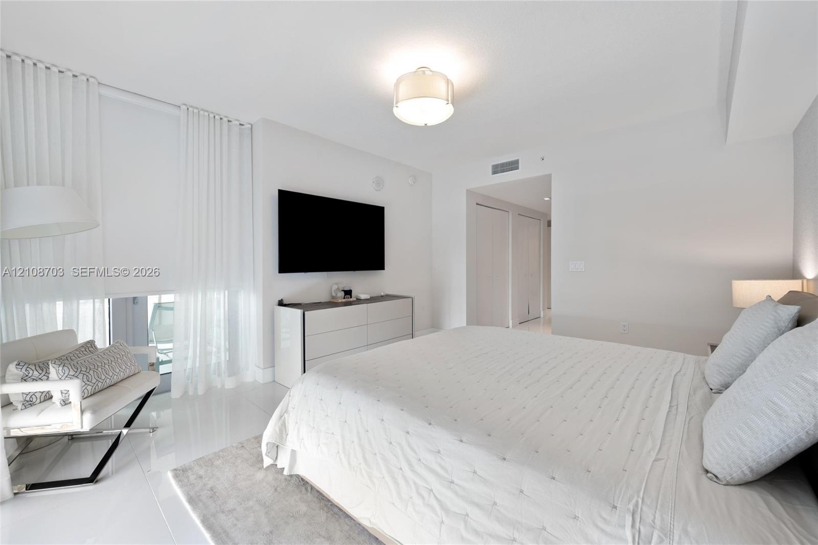 Bright bedroom featuring high-gloss tile flooring, floor-to-ceiling sheer window treatments, and a contemporary drum-style ceiling fixture