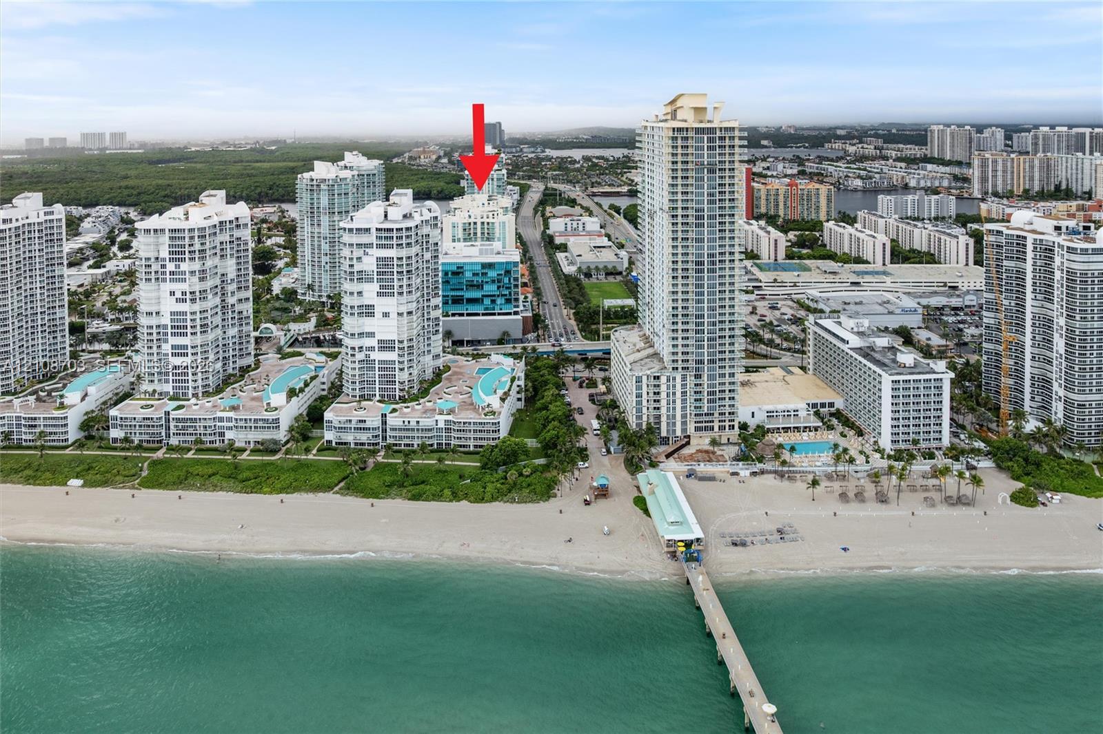 High-rise condominium building featuring glass exterior cladding, expansive terraces, and immediate proximity to the Atlantic coastline