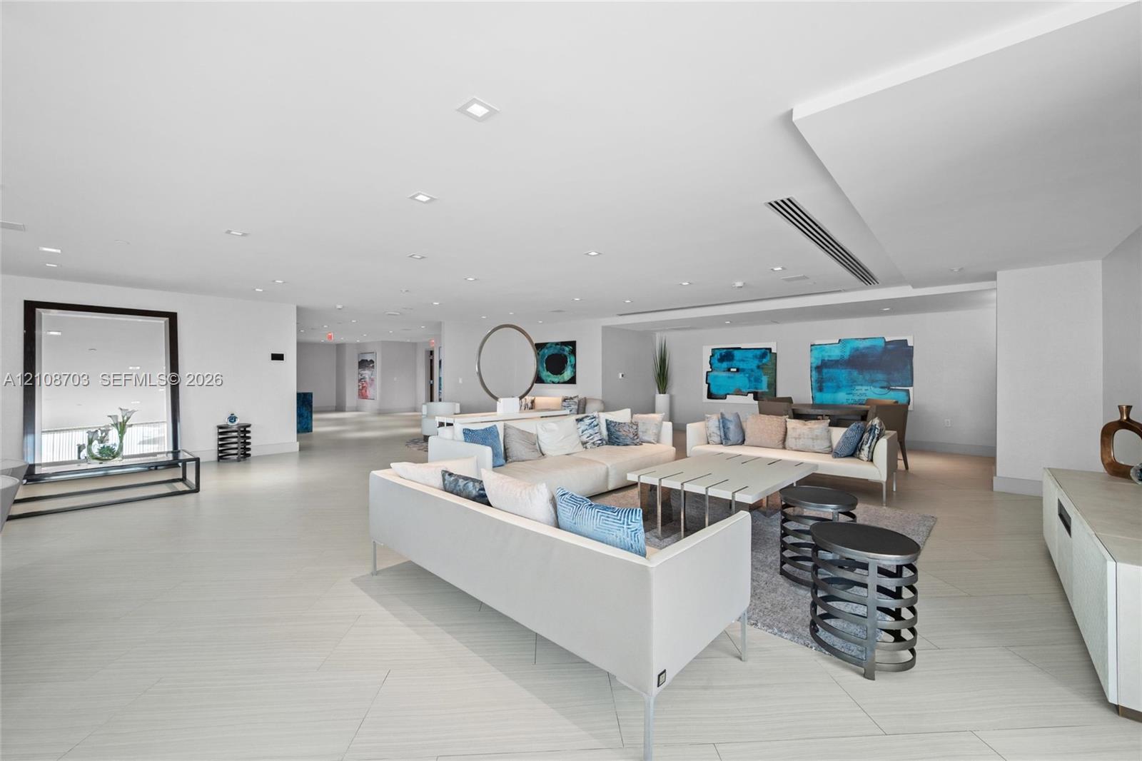 Expansive living area featuring porcelain tile flooring, recessed lighting, soffit ceiling detailing, and built-in linear HVAC registers