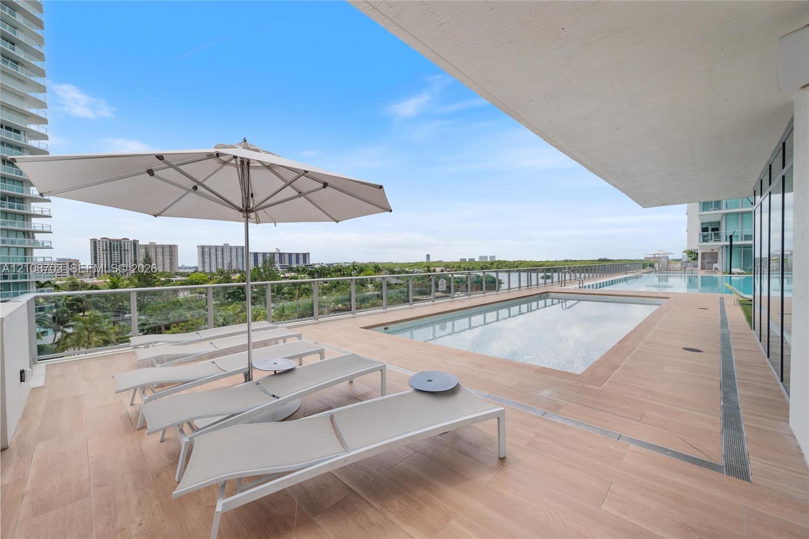 Private terrace featuring a rectangular swimming pool, wood-finish tile flooring, and a glass-paneled railing
