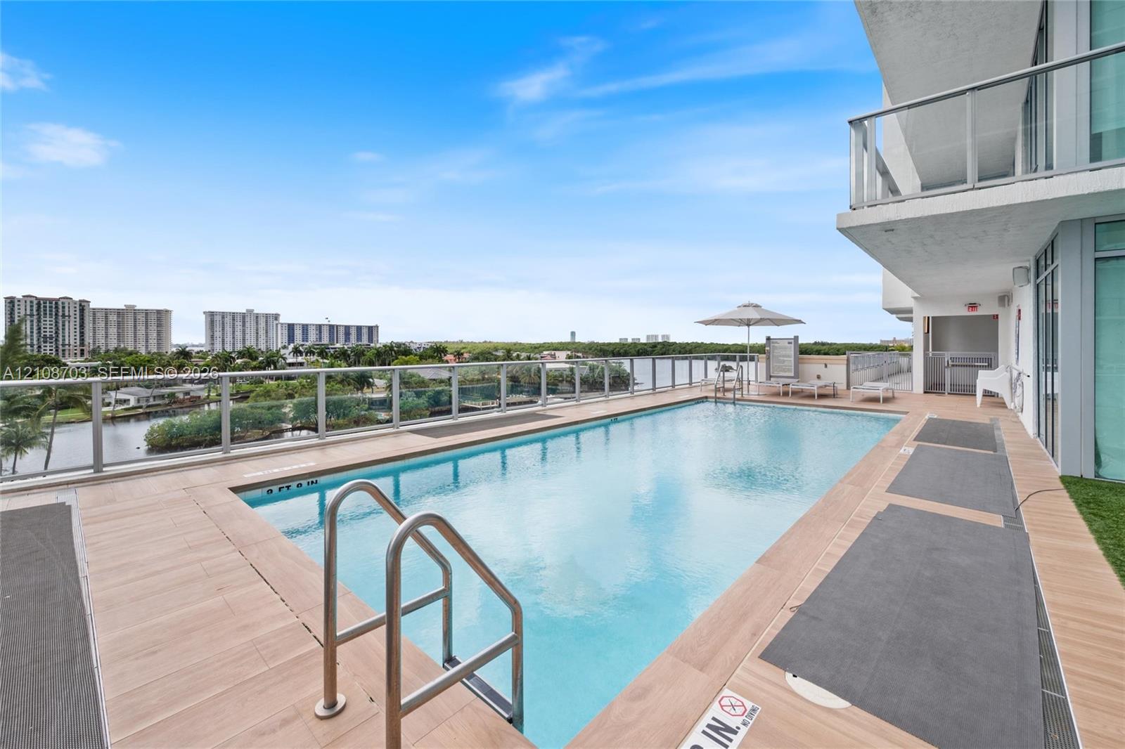 Elevated swimming pool featuring wood-finish decking, metal railing, and stainless steel ladder