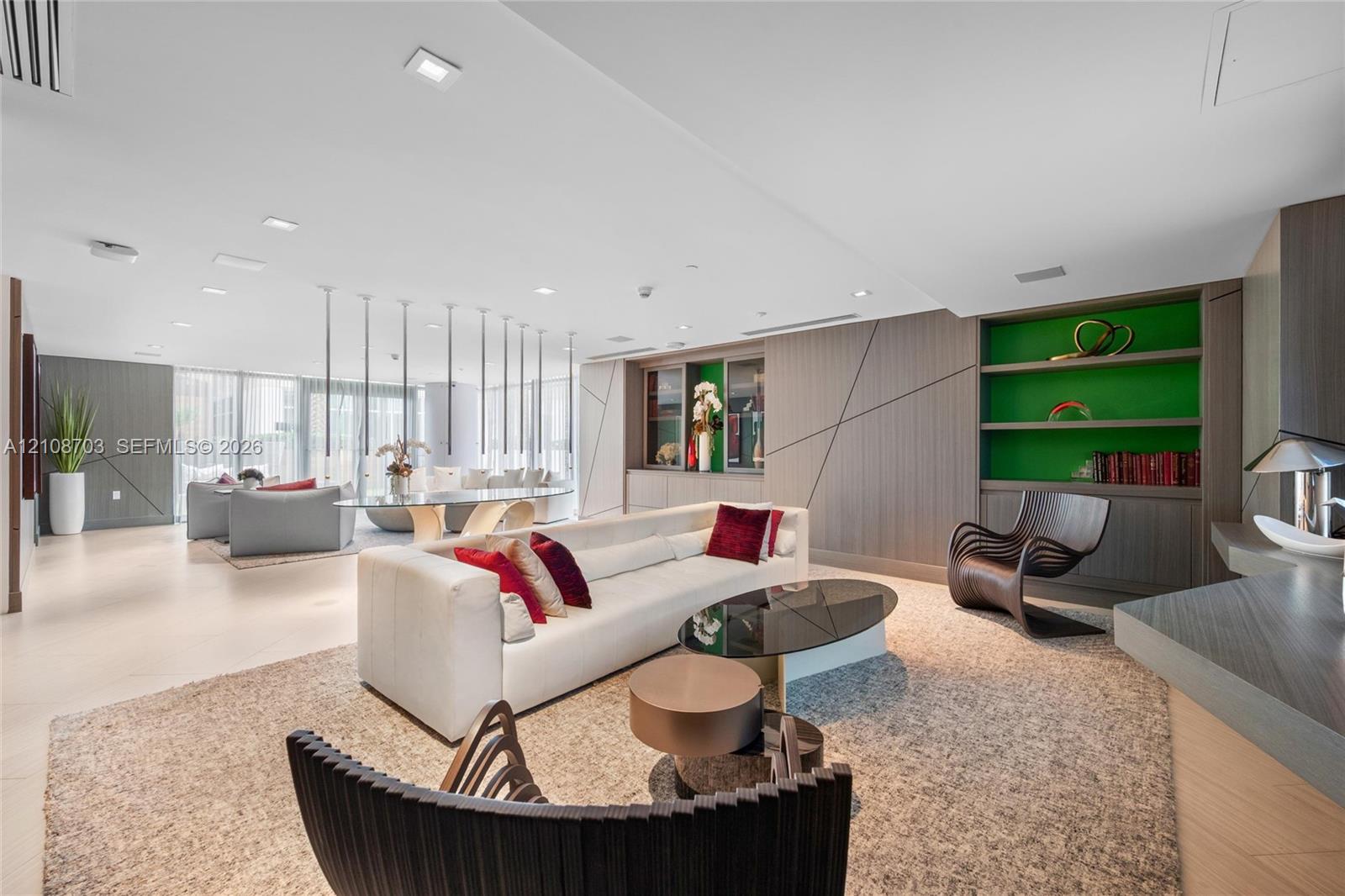 Open floor plan featuring recessed lighting, floor-to-ceiling windows, integrated wall paneling, and custom built-in shelving with a contrasting accent finish