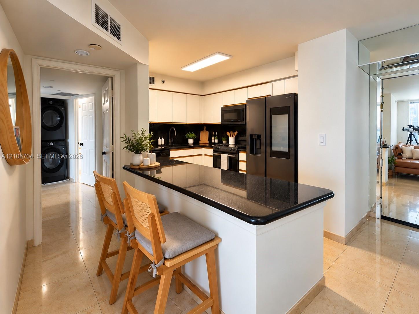 Kitchen featuring white cabinetry, black countertop, matching black appliances, and neutral tile flooring Kitchen featuring white cabinetry, black countertop, matching black appliances, and neutral tile flooring