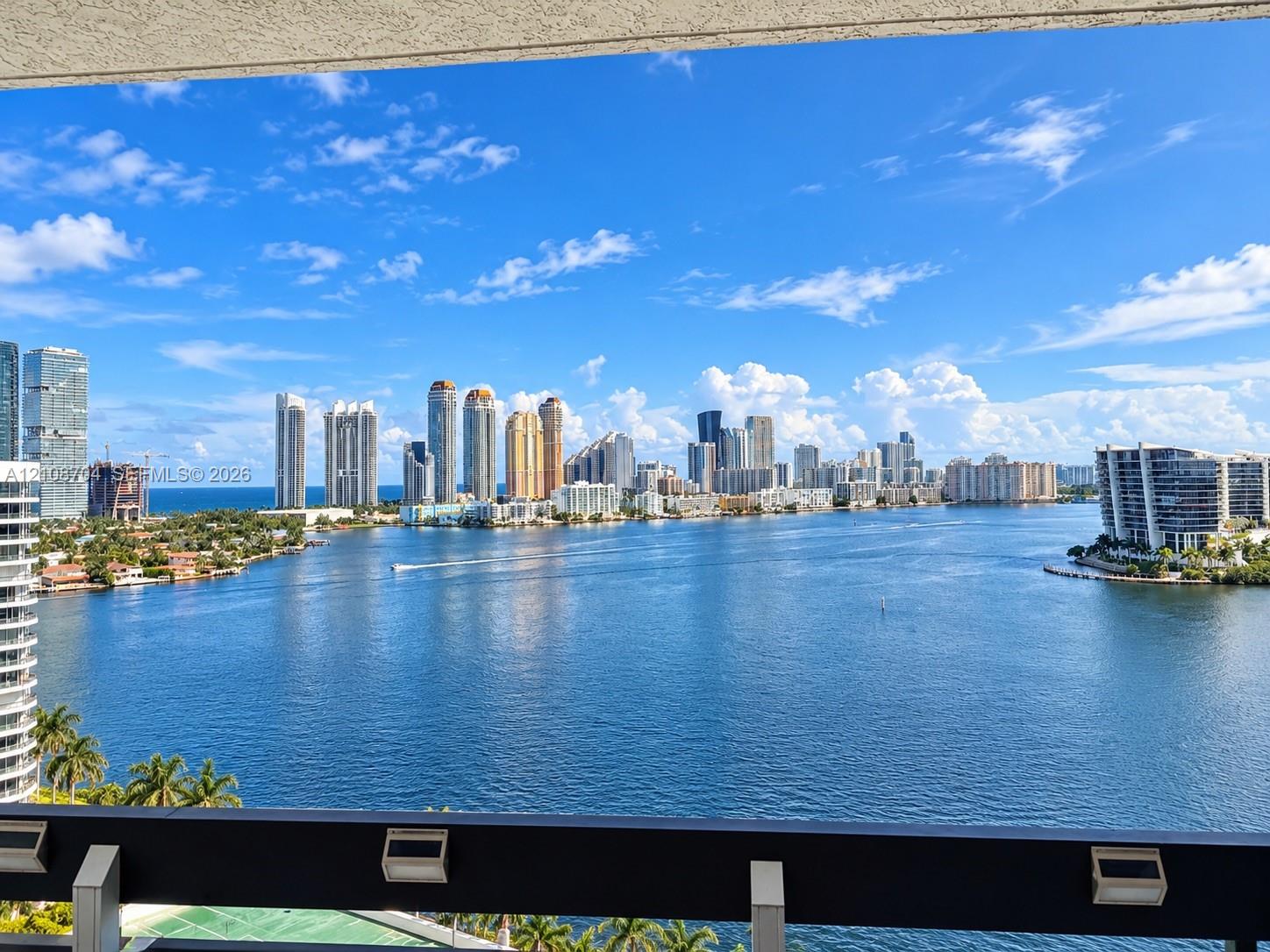 Outdoor balcony featuring a dark metal railing with integrated lighting, overlooking a wide expanse of water and a skyline Outdoor balcony featuring a dark metal railing with integrated lighting, overlooking a wide expanse of water and a skyline