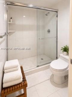 Walk-in shower featuring sliding glass doors, chrome hardware, integrated tile shelving, and tile flooring Walk-in shower featuring sliding glass doors, chrome hardware, integrated tile shelving, and tile flooring