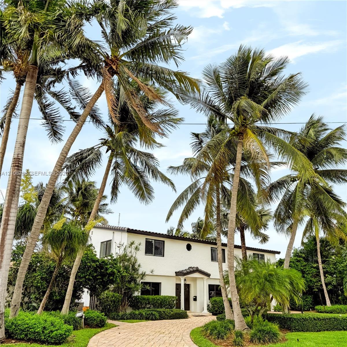 Two story home with circular driveway and tropical landscaping