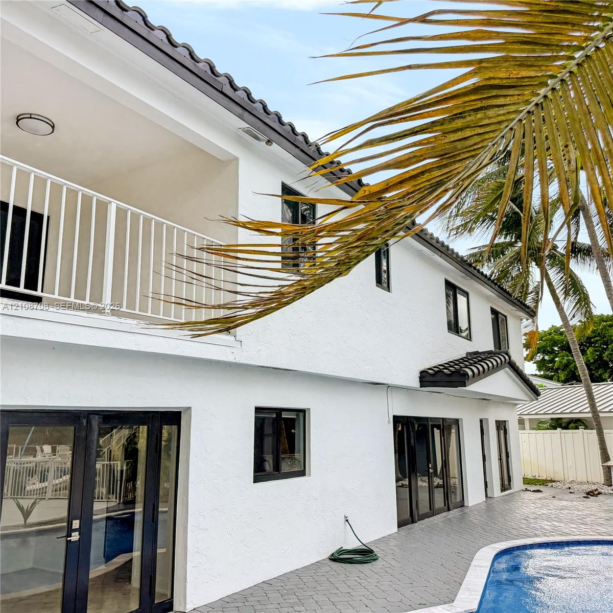 Two story white home with upper balcony and pool